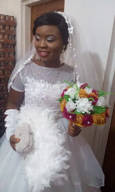 Nikjade bride in a beaded ivory ball gown with a feathered bouquet